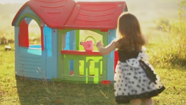 Девочка бегает на фоне игрушечного домика — стоковое видео