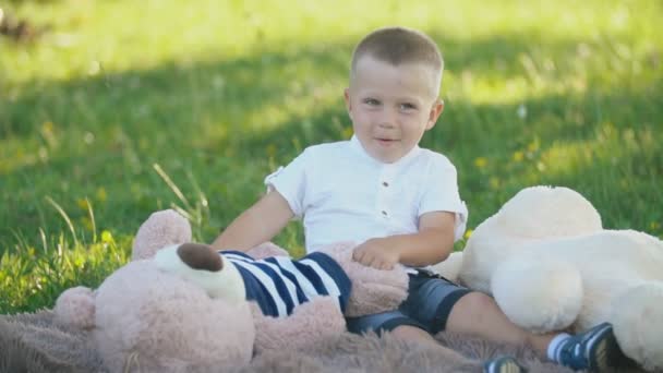 Garçon avec des jouets mous assis sur une couverture — Video