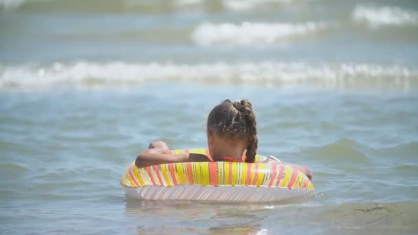 Chica con un círculo inflable se baña en el mar — Vídeos de Stock