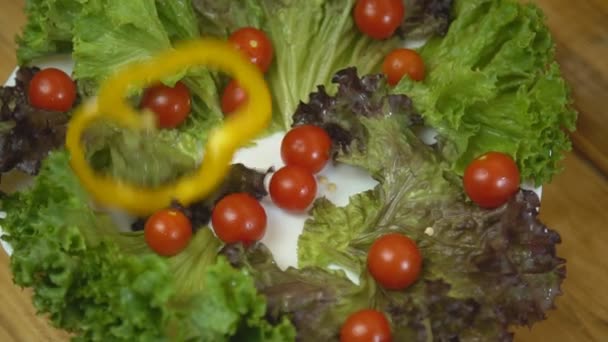 Rodajas de pimienta caen en un plato con tomates y lechuga — Vídeos de Stock