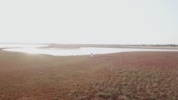 Fille dans une robe blanche promenades le long du bord de la mer — Video