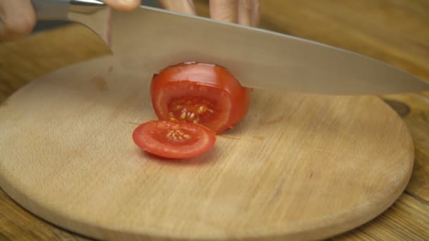 Vrouw snijdt tomaat met een mes — Stockvideo