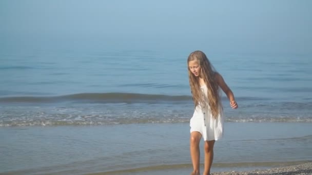 Little girl in a white dress walks near the sea — Stock Video