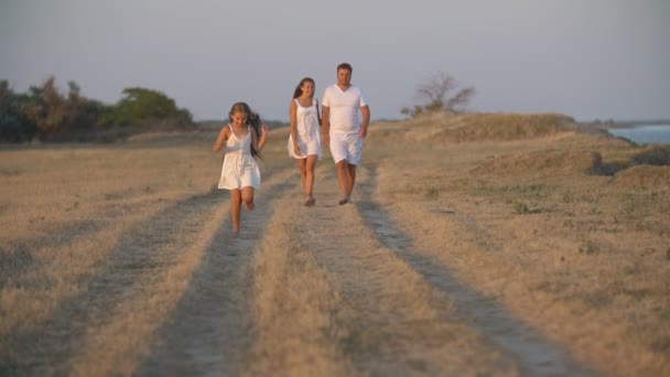 Familia en ropa blanca camina por un camino de tierra — Vídeos de Stock