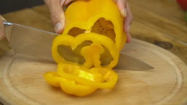 Різання жовтого перцю на дерев'яному столі — стокове відео