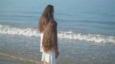 Anne ve kızı deniz kenarında geziniyorlar.