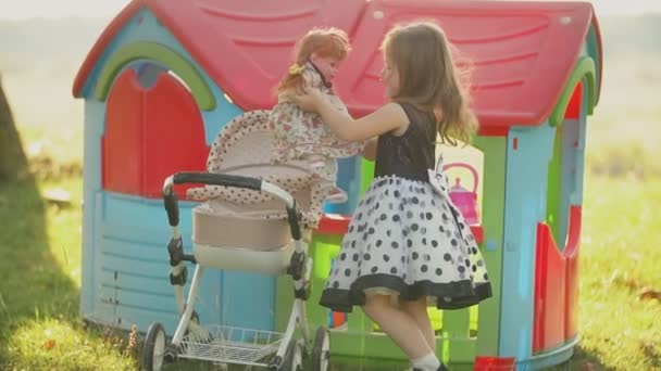 Petite fille joue avec une poupée près d'un chariot jouet — Video