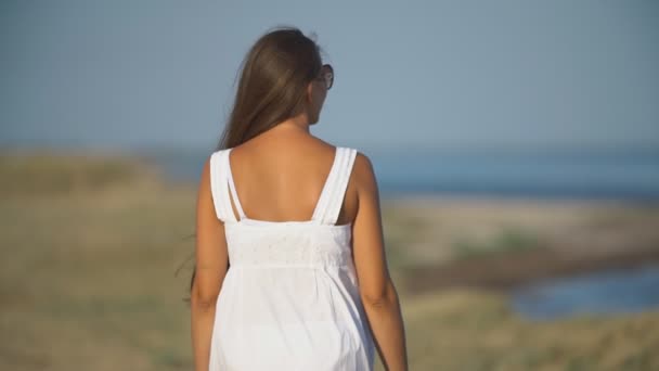 Mujer en vestido blanco y gafas de sol de pie y se ve — Vídeos de Stock