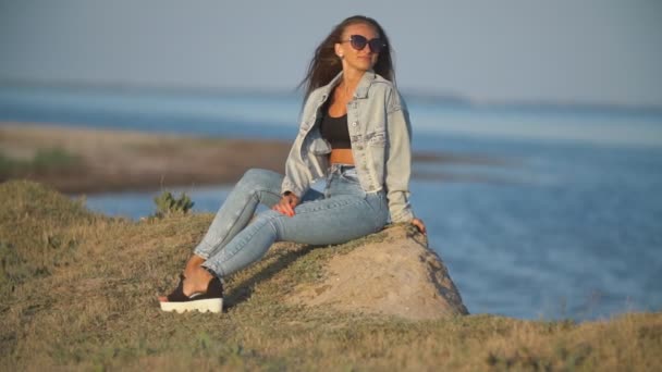 Девушка в джинсовой одежде на фоне моря — стоковое видео