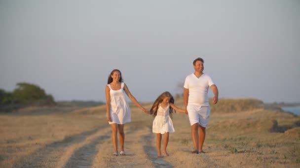 Familia en ropa blanca camina por un camino de tierra — Vídeos de Stock