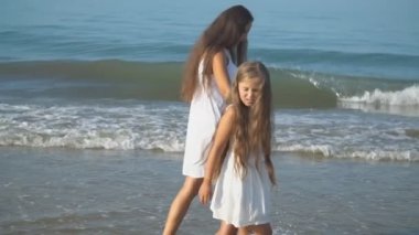 Anne ve kızı deniz kenarında geziniyorlar.