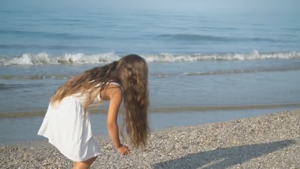 Kleines Mädchen im weißen Kleid geht am Meer spazieren — Stockvideo