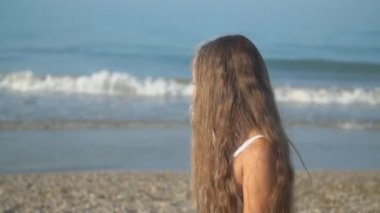 beyaz elbiseli küçük kız denize yakın yürüyor
