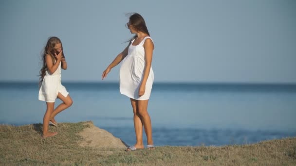 Mor med dotter i vita klänningar nära havet — Stockvideo