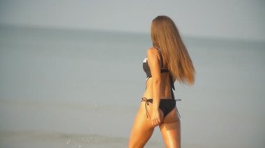 Mayolu kız deniz kenarında yürüyor.