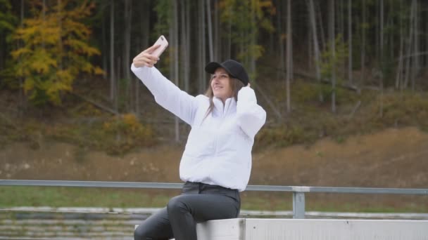 Menina em um boné leva uma selfie — Vídeo de Stock