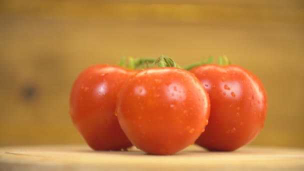 Los tomates giran sobre una mesa de madera — Vídeos de Stock