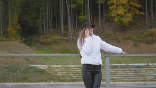 Дівчина в шапці розмовляє по телефону — стокове відео