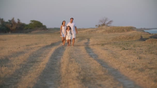 Family walks on a dirt road — ストック動画