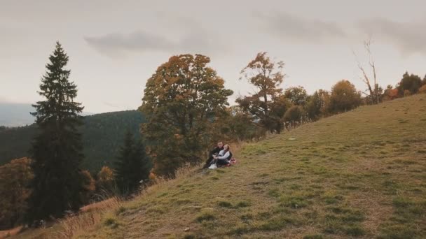 Pareja sentada en una colina y mirando a la distancia — Vídeos de Stock