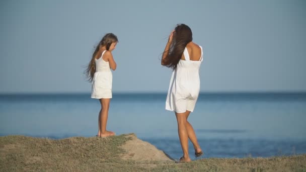 Мати з дочкою в білих сукнях біля моря — стокове відео