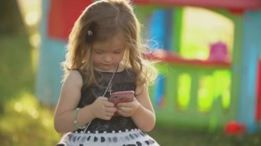 çocuk elinde bir telefon ile oturur