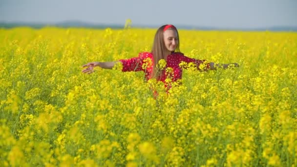 Chica camina a través del campo con flor de colza — Vídeo de stock