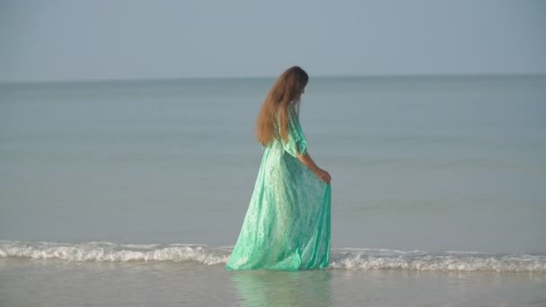 Bornozlu bir kadın deniz kenarında yürüyor. — Stok video