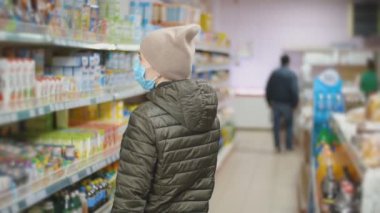 Tıbbi maskeli kadın ürünler alıyor.