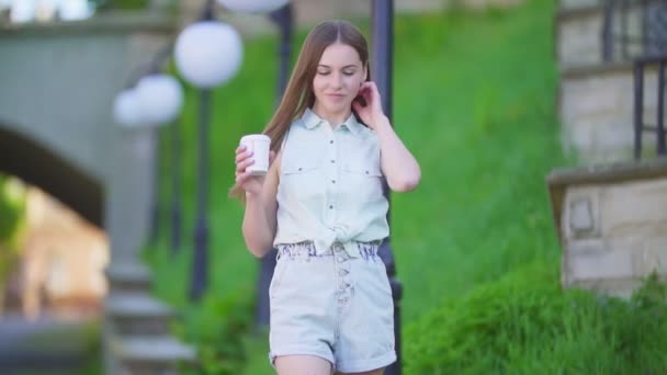 Mooi meisje in korte broek en een plastic beker — Stockvideo