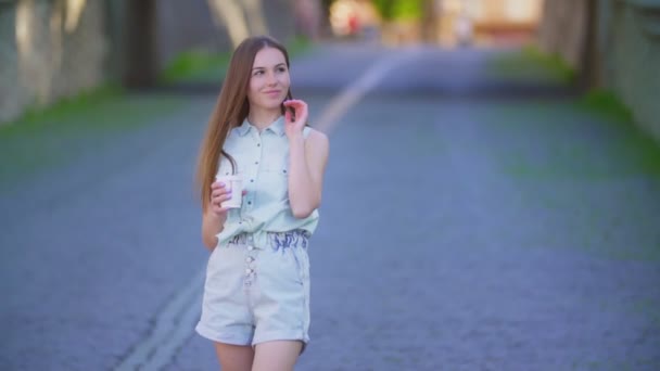 Hermosa chica en pantalones cortos y una taza de plástico — Vídeos de Stock