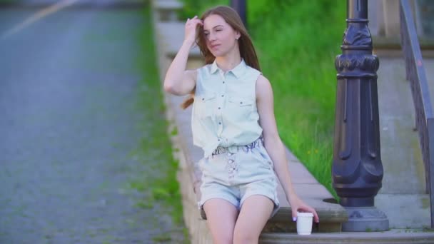 Mooi meisje in korte broek en een plastic beker — Stockvideo