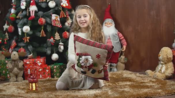 Chica con una almohada en el fondo del árbol de Navidad — Vídeos de Stock