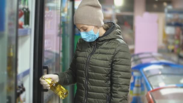 Una mujer en una máscara toma mercancías del refrigerador — Vídeos de Stock