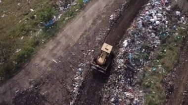 Buldozer çöpü bir yığının üzerine atıyor.