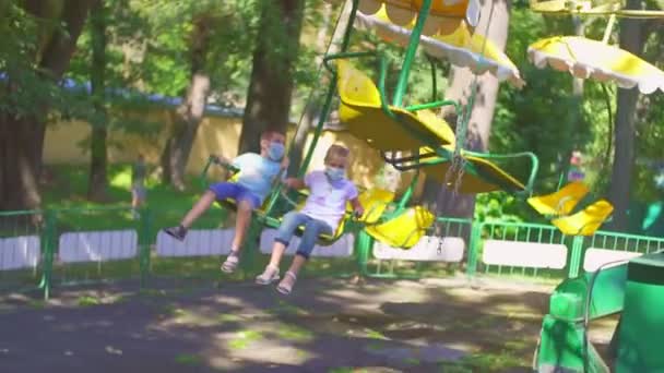 Děti jezdí na atrakci v parku — Stock video