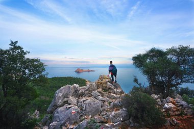 Deniz günbatımı. Yaya turist kayaya maliyeti ve horizon adlı görünüyor.