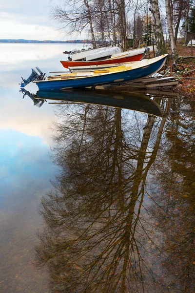 Autumn Finnish landscape. Boats on a reservoir. Trees and boats are reflected in water in the foreground