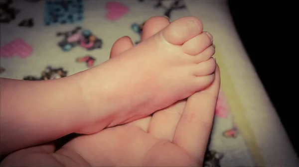 母親の手の手のひらの赤ちゃんの足は — ストック写真