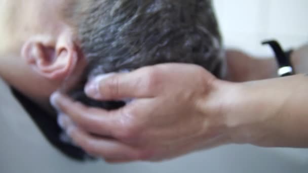 在美发沙龙的水槽内将洗发水涂抹在男性头部 — 图库视频影像