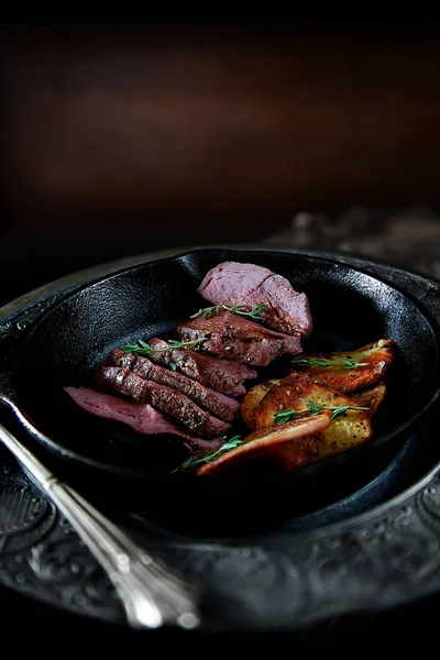 揚げジャガイモのスライスとタイムのハーブ焼き野生鹿フィレ肉 コピー スペースの寛大なご宿泊で暗い 素朴な背景に撮影します — ストック写真