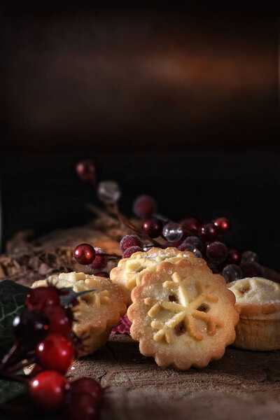 Seasonal festive traditional mince pies with marinated brandy filling shot against a dark rustic background with generous accommodation for copy space.