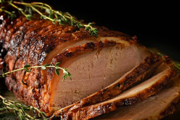 Close-up of sliced roast pork with thyme herb garnish, ready to serve. the perfect image for your bistro or restaurant cover art with copy space.