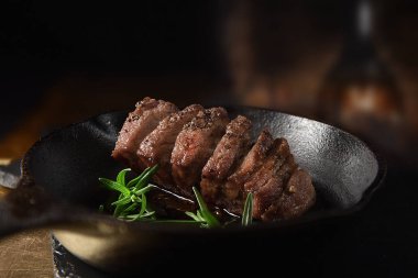 Yaban domuzu Fileto Biftek biberiye bitki ile demir tavada. Seçici odak ve kopya alanı. Bistro menüsü kapak resmi için mükemmel görüntü.