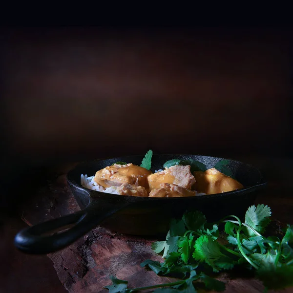 Traditional Indian cuisine, Chicken Curry with cilantro herb garnish (coriander) and basmati rice shot against a rustic background with accommodation for copy space. The perfect image for your Indian menu cover art.