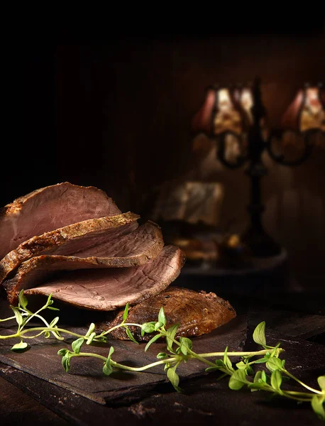 Prime roast beef, sliced and ready to serve with thyme herb garnish. Shot against a rustic background with generous accommodation for copy space.