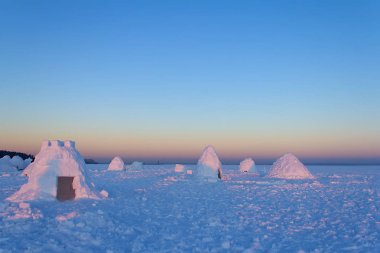 Kampa birkaç karlı evlerin bir Eskimo batan güneşin ışınları denilen oluşur.