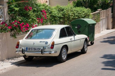 Santa Ponsa, Mallorca, İspanya - 24 Temmuz 2013: Retro araba Mg Bgt çiçekli bir duvarının yakınında park edilmiş ve palmiye yaprakları.