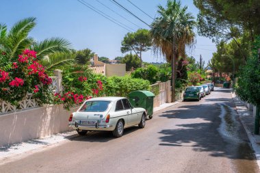 Santa Ponsa, Mallorca, İspanya - 24 Temmuz 2013: Retro araba Mg Bgt çiçekli bir duvarının yakınında park edilmiş ve palmiye yaprakları.