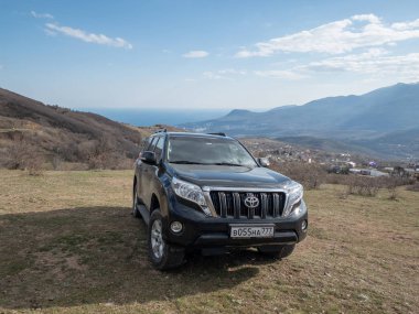Alushta, Kırım Cumhuriyeti - Mart 23, 2019: Siyah off-road araba Toyota Land Cruiser Prado doğada park